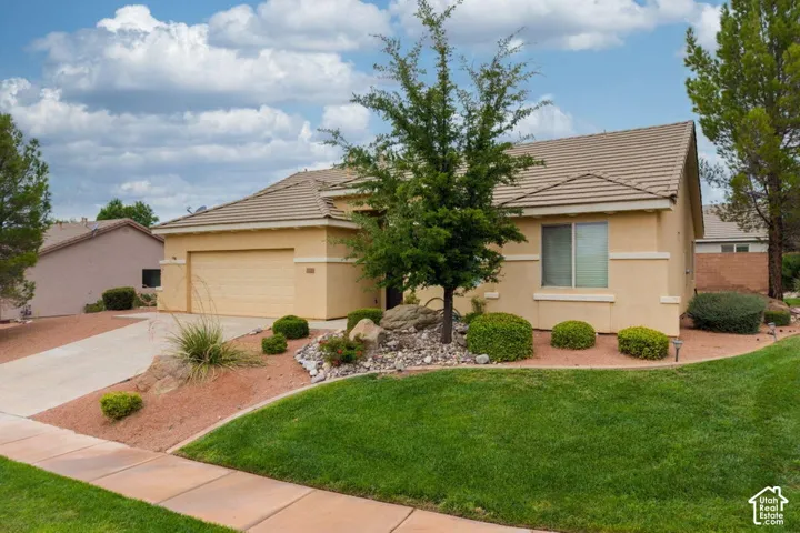 Stucco exterior with a tiled roof, attached garage, and a concrete driveway