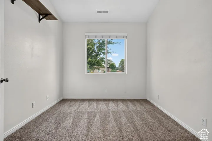 Neutral wall finishes, patterned carpeting, and a single window with blinds