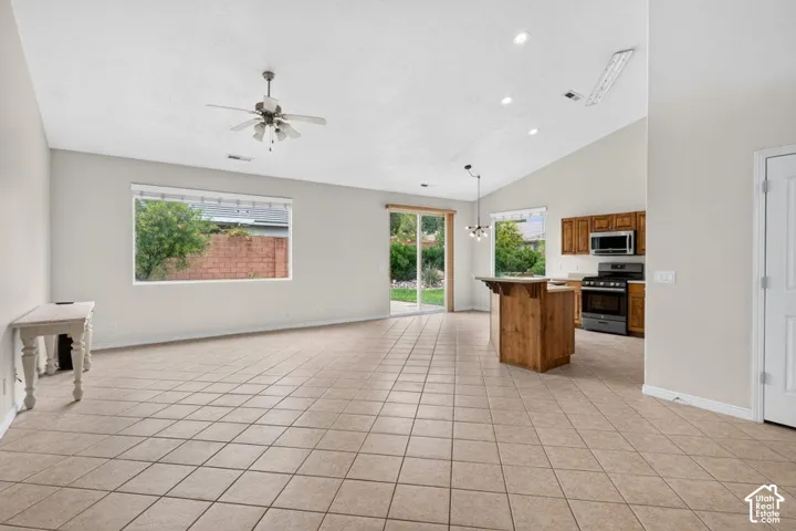 Vaulted ceilings, neutral tile flooring, and recessed lighting create an open living space