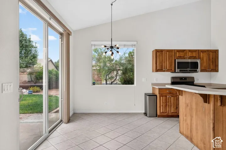Vaulted ceilings, tiled flooring, wood cabinetry, stainless steel microwave, and a glass sliding door