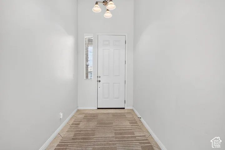 Front entry with a white door, a sidelight with blinds, and a three-light ceiling fixture