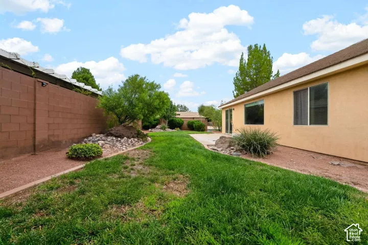 Expansive grassy area with rock landscaping, a block wall perimeter, and a stucco exterior