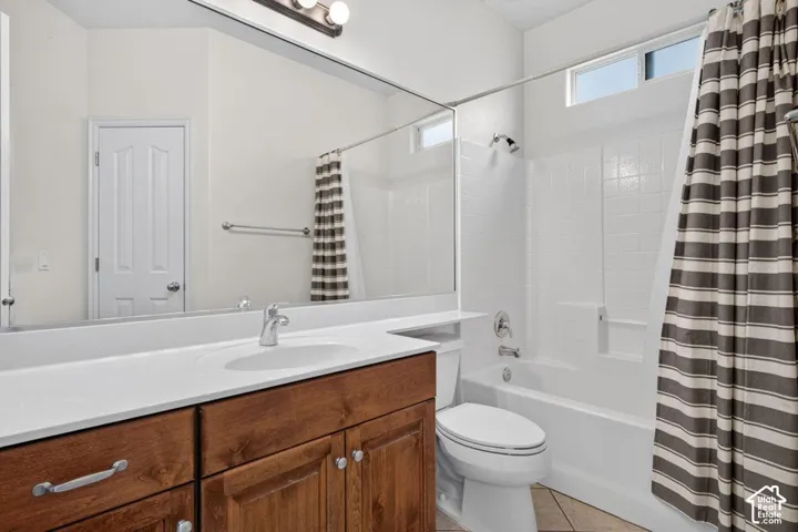Bathroom featuring a wood-finish vanity with an integrated sink, a large mirror, a full bathtub with a shower, and a high window