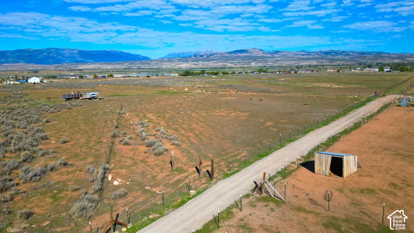 Expansive rural acreage with a gravel drive, fencing, and a utility shed