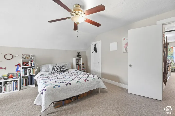Carpeted flooring, vaulted ceiling, and overhead ceiling fan with integrated lighting