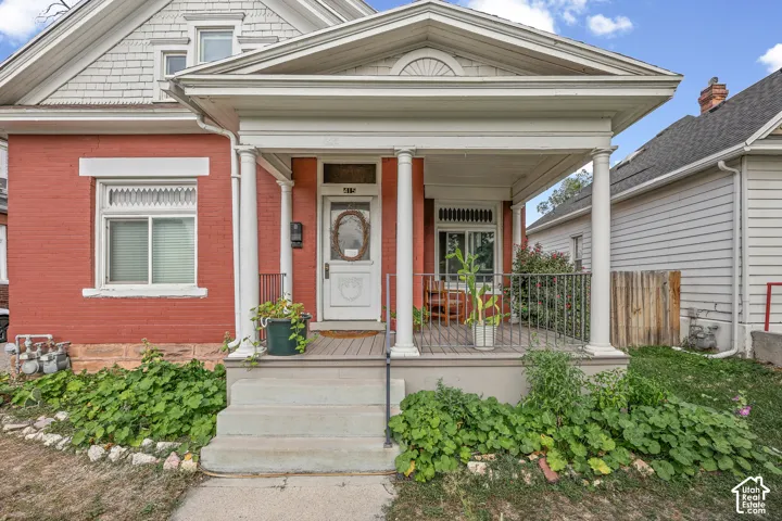 Red brick exterior with white trim, a covered front porch, and decorative columns