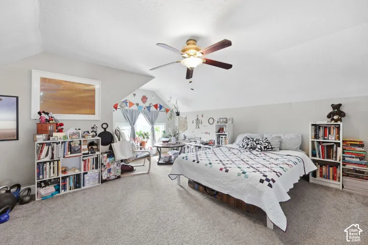 Sloped ceilings, ceiling fan, and carpeted flooring