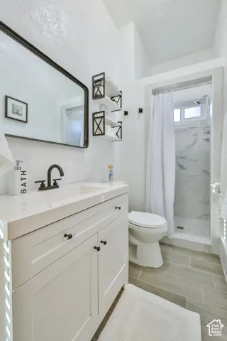 Spa-inspired bathroom featuring a white vanity with multiple drawers and matte black hardware, a vessel sink with a matte black faucet, and a quartz countertop