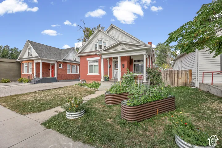Brick facade home with white trim, a covered front porch, and raised garden beds
