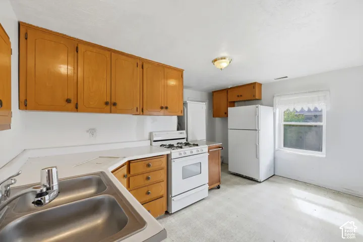 Kitchen featuring wood cabinetry, a dual basin stainless steel sink, a gas range, and a window for natural light