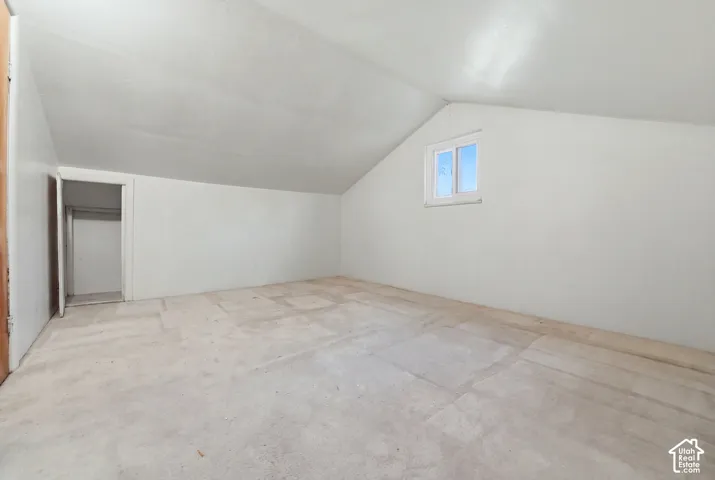 Sloped ceiling room featuring a window with a white frame and a partial closet opening