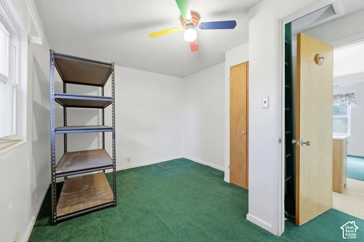 Carpeted flooring, a window, a built-in closet, and a ceiling fan