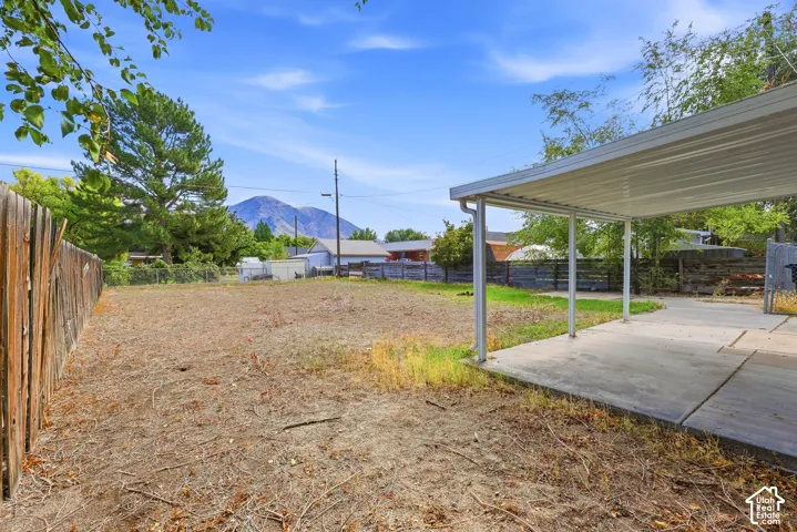 Expansive yard with wood fencing, concrete patio, and attached metal carport