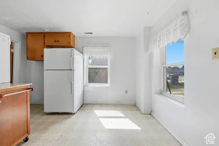 Kitchen space featuring wood cabinetry, white appliances, and a light-colored flooring