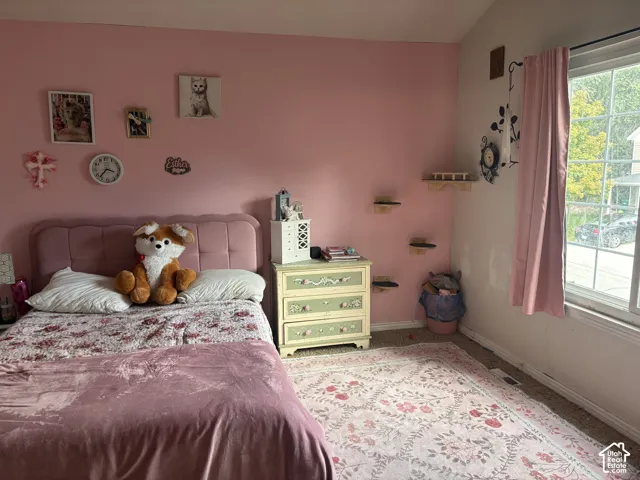 Window with natural light, wall-mounted shelving, upholstered headboard, and wood-finish nightstand