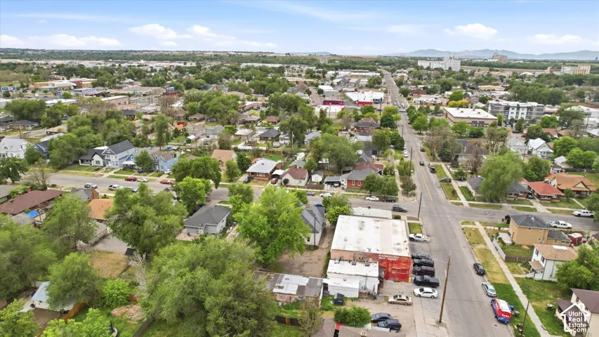Aerial perspective showcasing a developed urban area with varied residential and commercial structures, multiple streets, and distant mountains