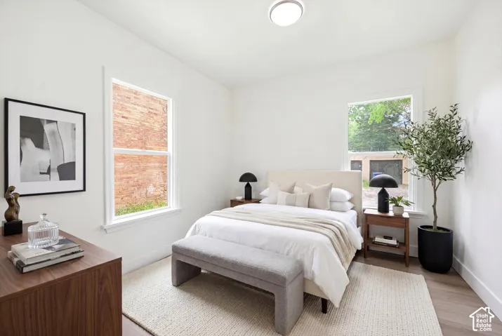 White walls with two single-hung windows, light wood-finish flooring, and a flush mount ceiling light