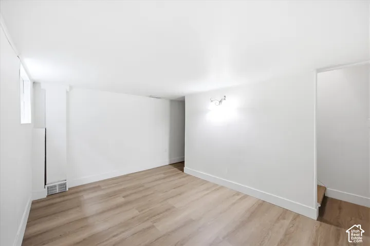 Light wood-finish flooring, white walls, and a built-in wall sconce