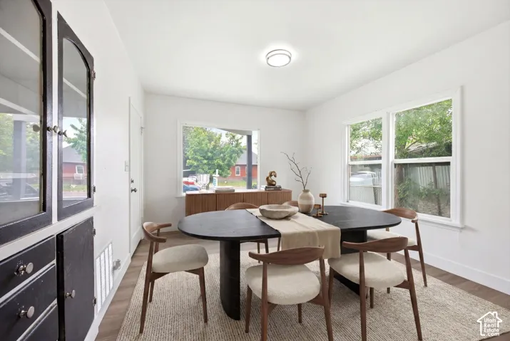 Built-in cabinetry with glass-front uppers, wood-finish flooring, white walls, and multiple windows