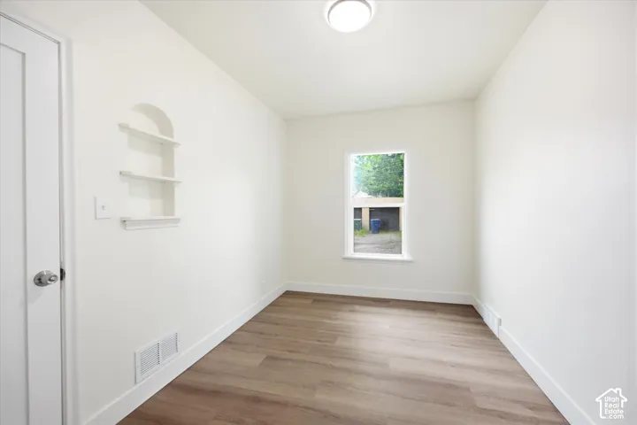 Recessed wall shelving, wood-finish flooring, and a single window