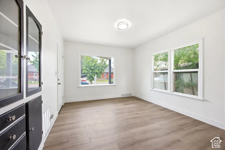 Wood-finish flooring, white walls, multiple windows with white trim, built-in cabinetry with glass panels, and a ceiling-mounted light fixture