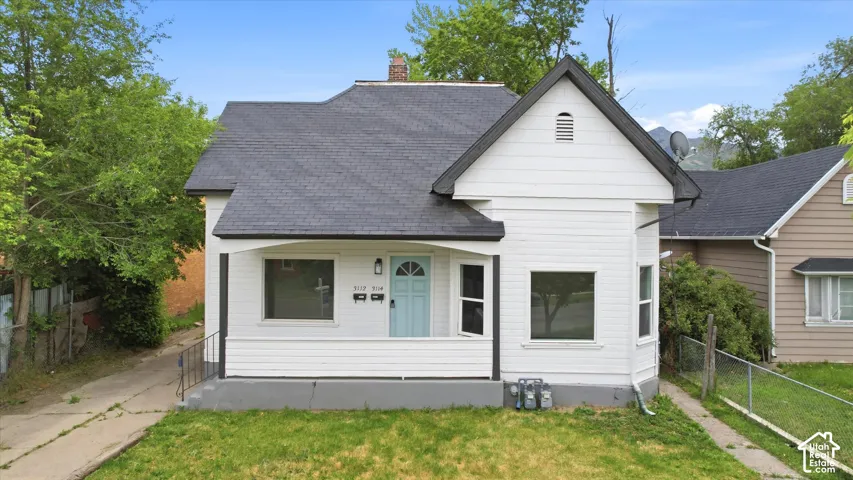 White siding exterior with a dark shingle roof and a light blue entry door
