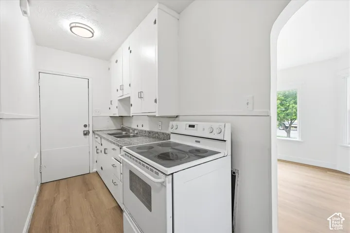 White cabinetry, wood-finish flooring, and a built-in range