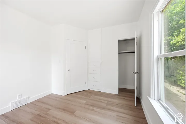 Wood-finish flooring, built-in cabinetry, white trim, and a double-hung window