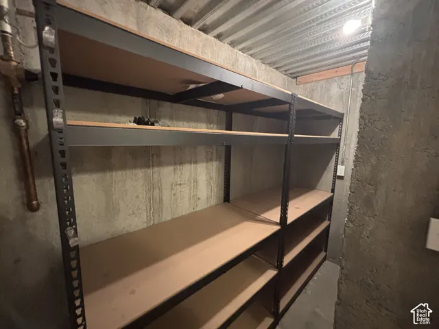 Built-in metal shelving units with wood-finish surfaces, concrete walls, and overhead lighting