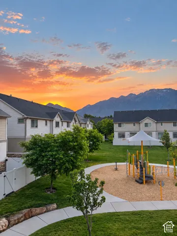 Community green space with playground structure, paved walking path, and mature trees