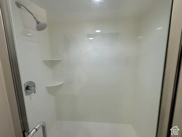Enclosed shower with a silver-finish showerhead, chrome-finish mixer, and integrated shelving