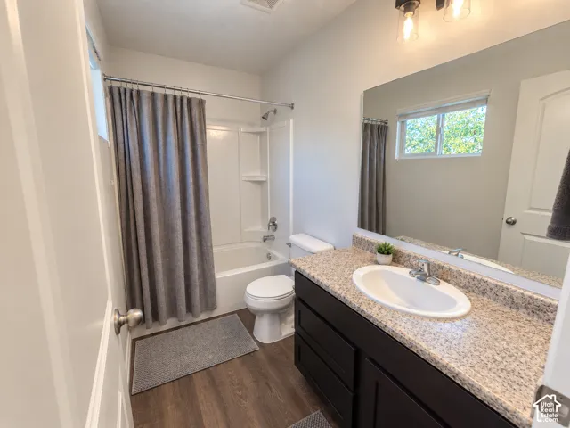 Bathroom featuring a vanity with a granite-look countertop, integrated sink, dark wood-finish cabinetry, and wood-finish flooring
