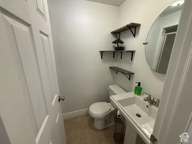 Pedestal sink with chrome faucet, wall-mounted oval mirror, and three corner shelves