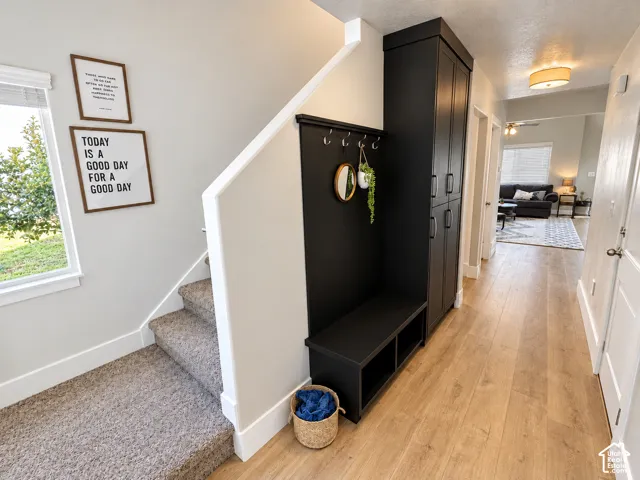 Entryway featuring wood-finish flooring, a built-in black storage unit, black bench seating, and a carpeted staircase