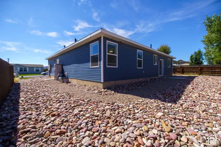 Exterior featuring dark blue horizontal siding, white trim, multiple windows, and a fenced perimeter