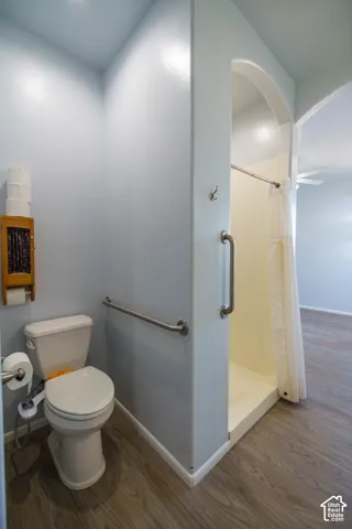Walk-in shower with grab bars, toilet with grab bar, and wood-finish flooring