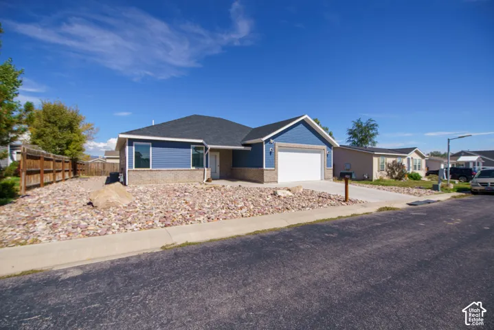 Single-story residence featuring blue siding, stone-finish accents, and an attached garage