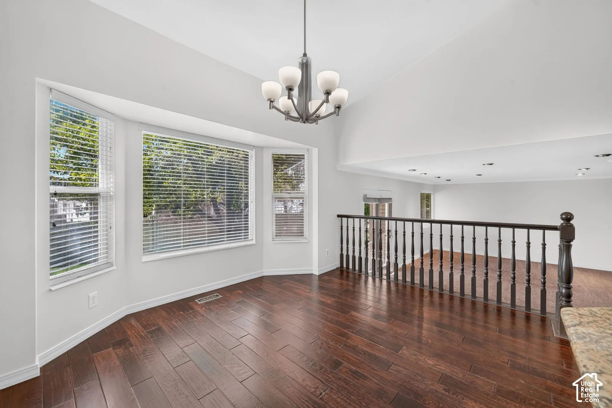 Bay window with multiple panels, vaulted ceiling, wood-finish flooring, and an open upper-level railing
