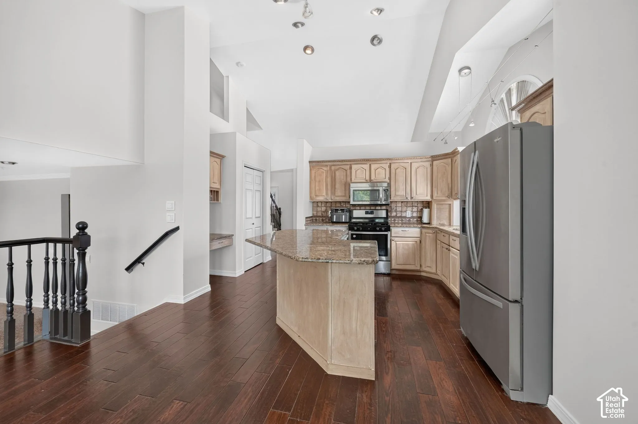 Kitchen featuring wood-finish flooring, a kitchen island with stone countertop, wood cabinetry, and stainless steel appliances