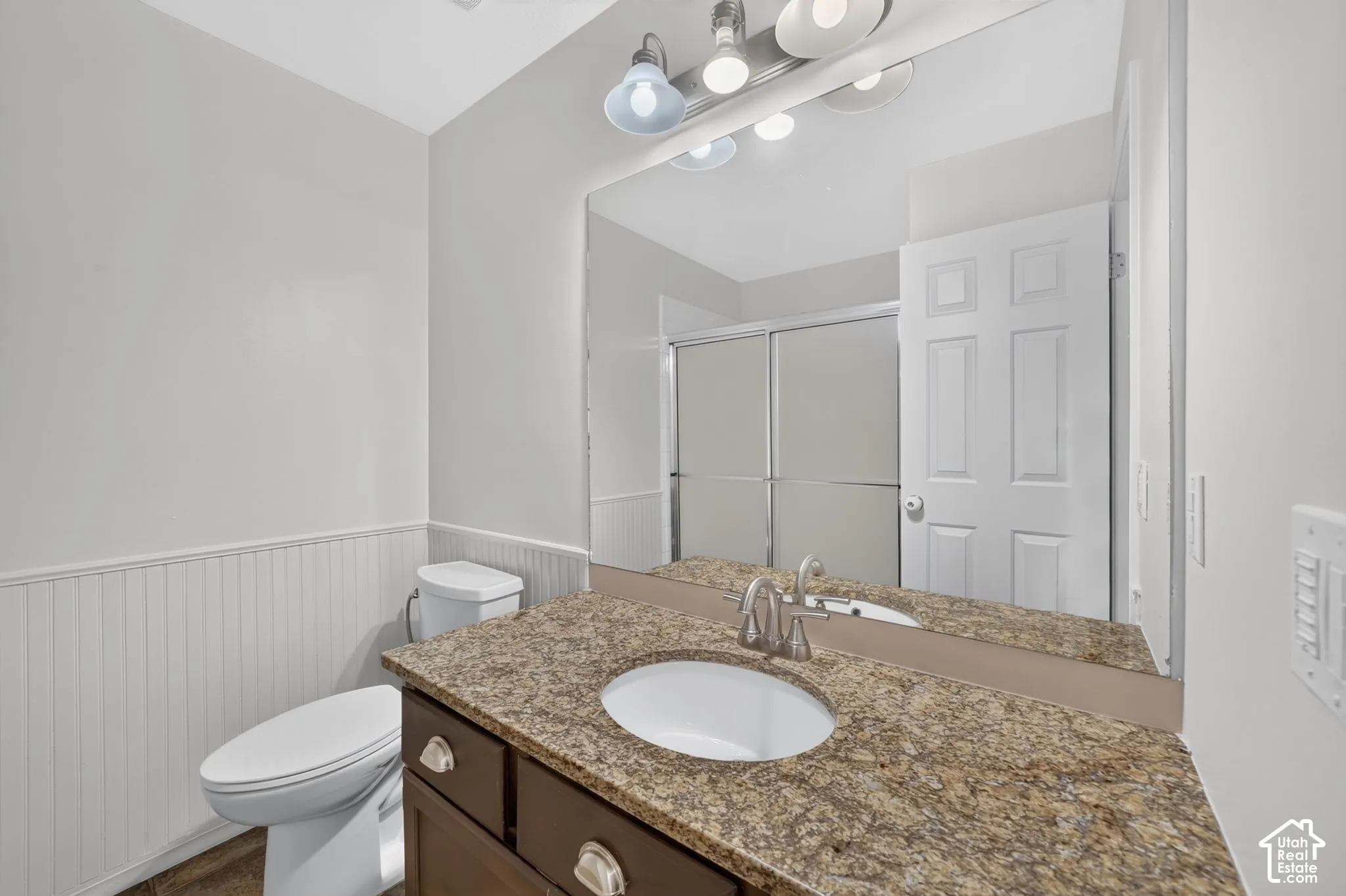 Vanity with granite countertop, integrated sink, and wood-finish cabinetry