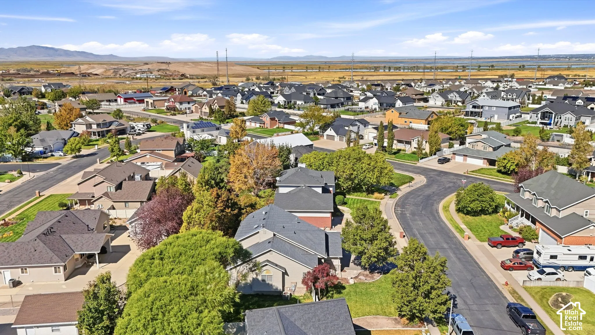 Aerial perspective of a residential community featuring varied home styles, mature landscaping, and paved streets