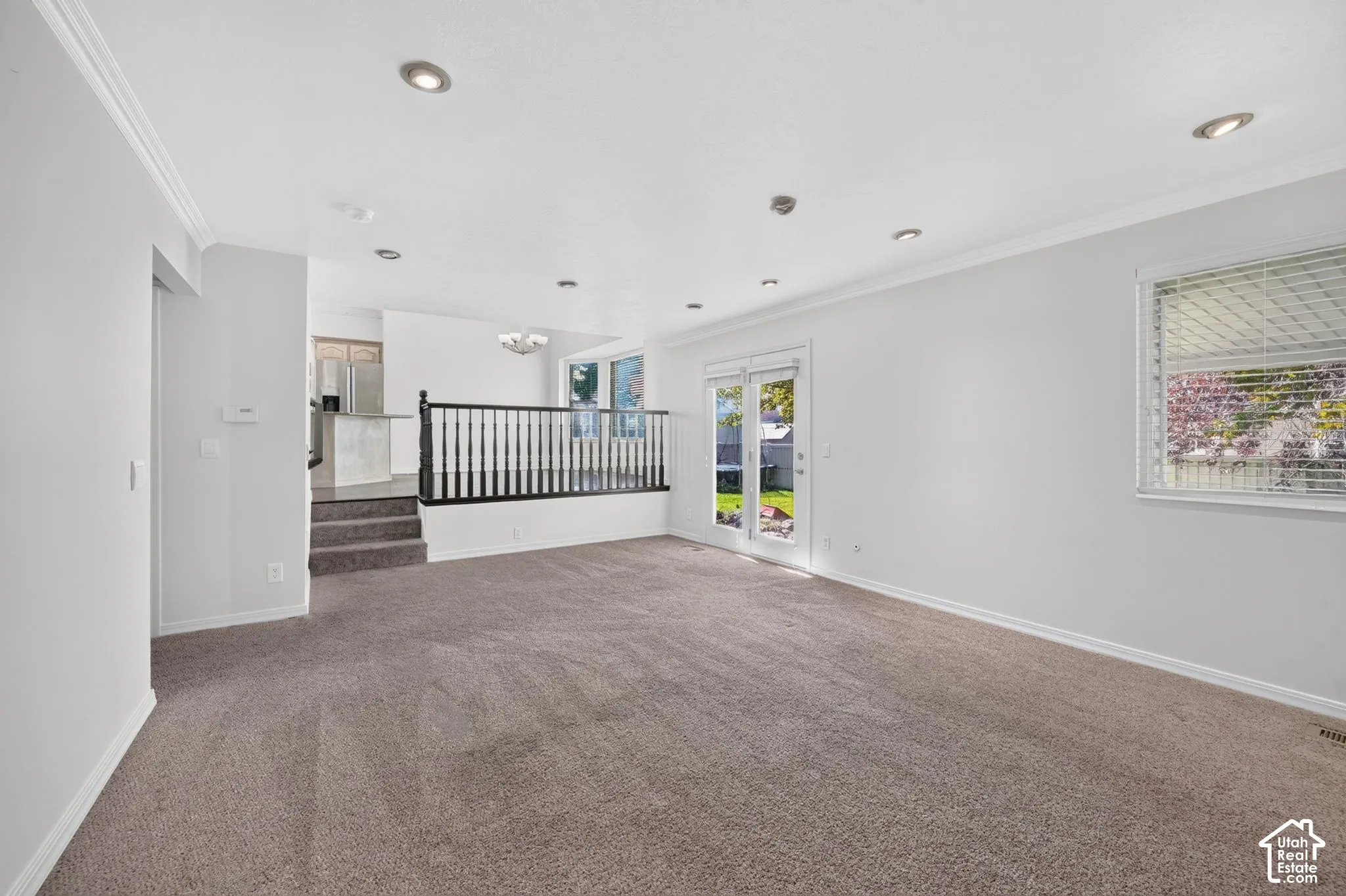 Recessed lighting, crown molding, double glass patio doors, window with blinds, and stair railing with balusters