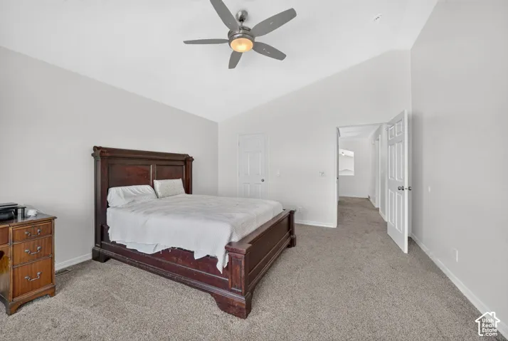 Vaulted ceiling with a ceiling fan light fixture, light gray walls, and gray carpet flooring