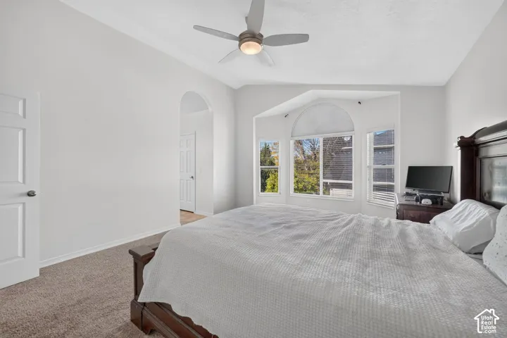 Bay window with arched transom, textured carpeting, and a ceiling fan with integrated lighting
