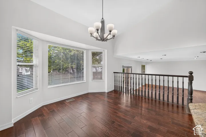 Bay window with multiple panels, vaulted ceiling, wood-finish flooring, and an open upper-level railing