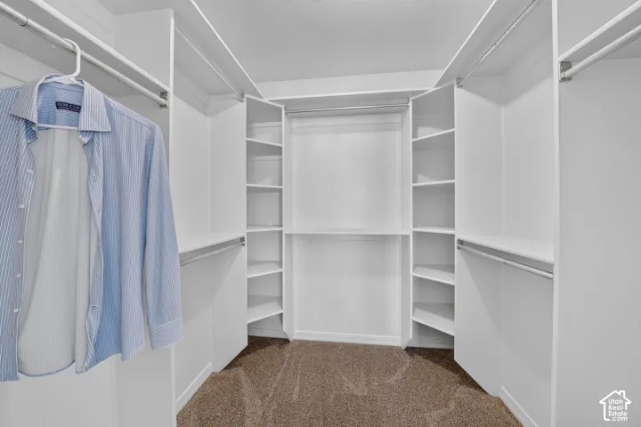 Walk-in closet featuring built-in shelving, multiple hanging rods, and neutral-toned carpeting
