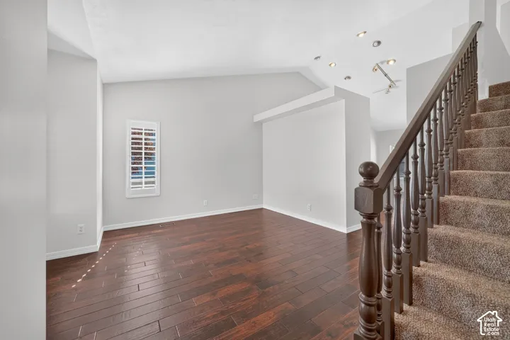 Wood-finish flooring, vaulted ceilings, plantation shutters, recessed lighting, and a carpeted staircase with a wood handrail