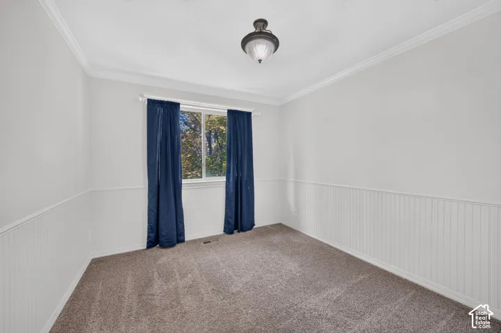 Crown molding detailing, white walls, wainscoting, recessed window, and a flush mount light fixture
