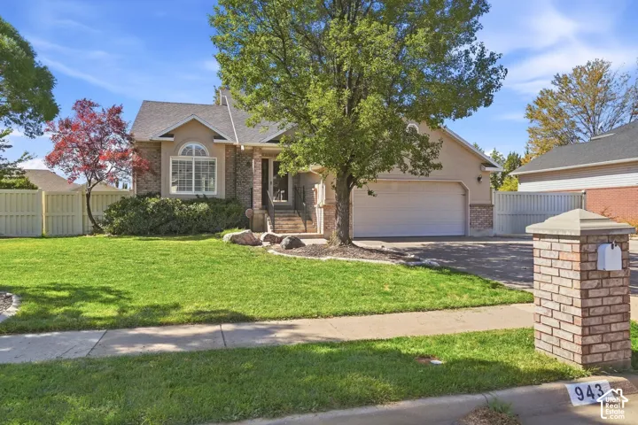Stucco and brick facade with an arched window, attached garage, and a brick mailbox