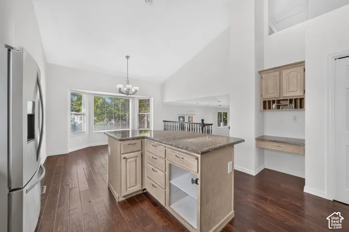 Wood-finish flooring, high vaulted ceilings, bay window, island with granite-style countertop, and built-in desk with cabinetry